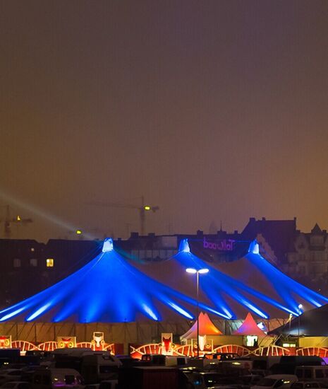 Panoramablick auf das Winter Tollwood Gelaende auf der Theresienwiese im Hintergrund die Paulskirche bei Nacht 